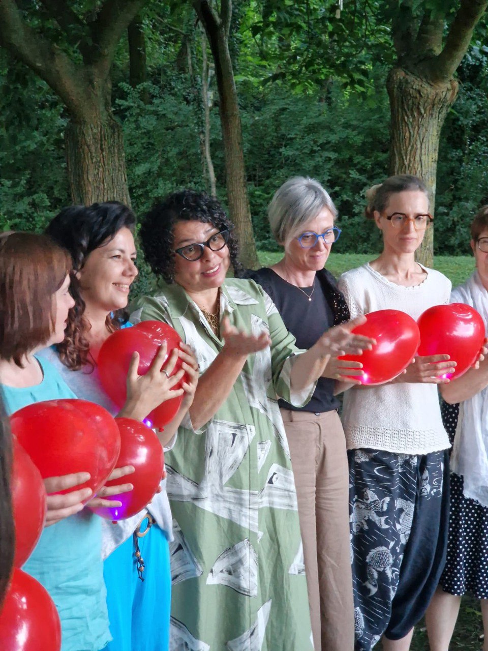 Donne in cerchio con palloncini rossi a forma di cuore