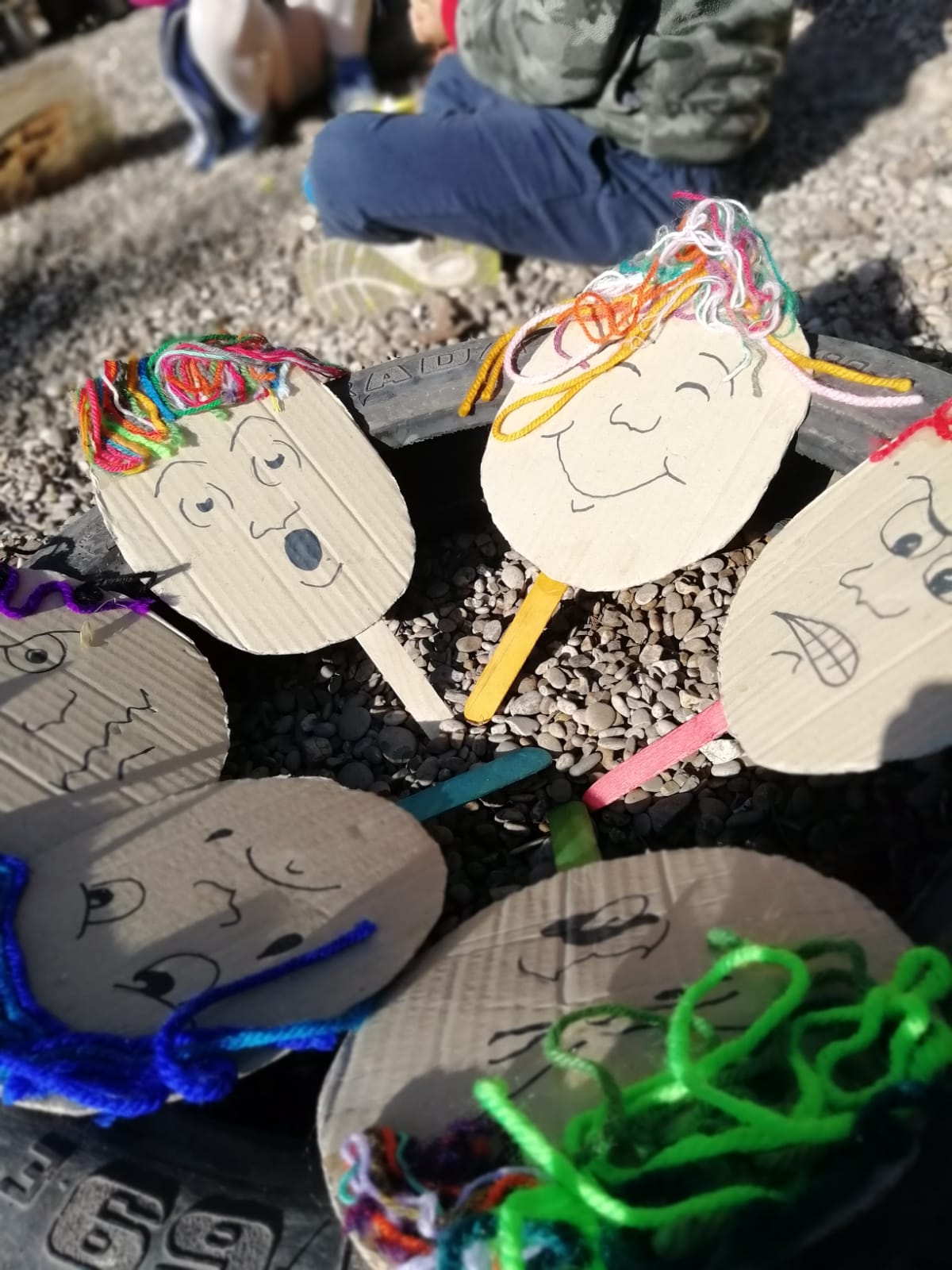Volti di cartone con espressioni emotive create dai bambini