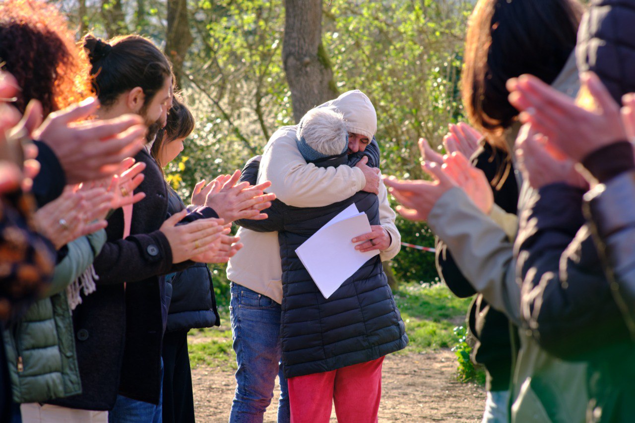 Due persone si abbracciano mentre la comunità intorno applaude